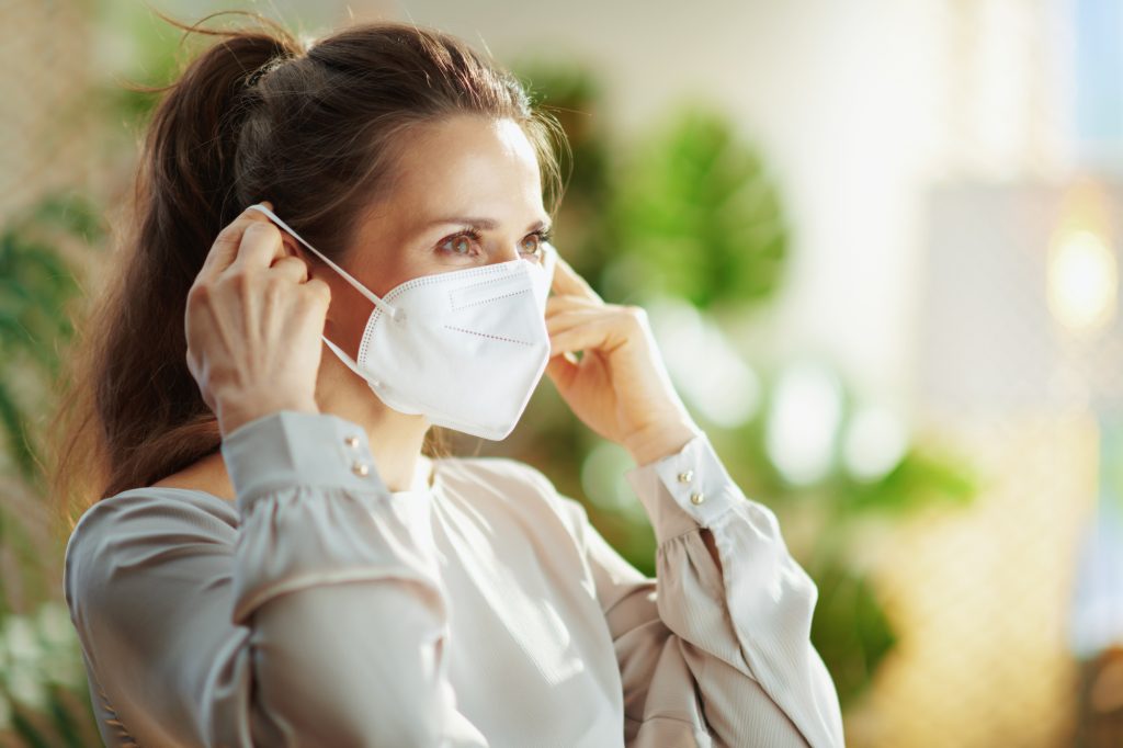 coronavirus pandemic. trendy woman in grey blouse wearing ffp2 mask.